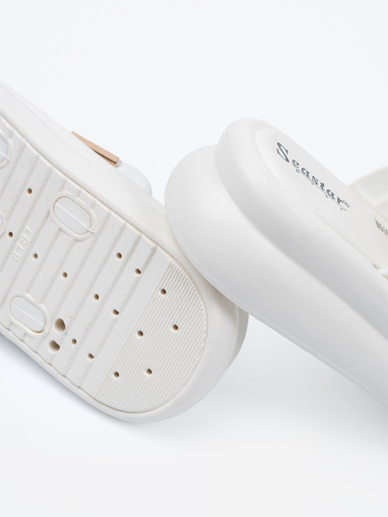 Weiße Pantoletten mit goldenen Schnallen auf der Plattform