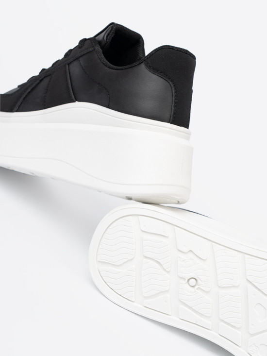 Klassische schwarze Sneakers mit dicker Sohle