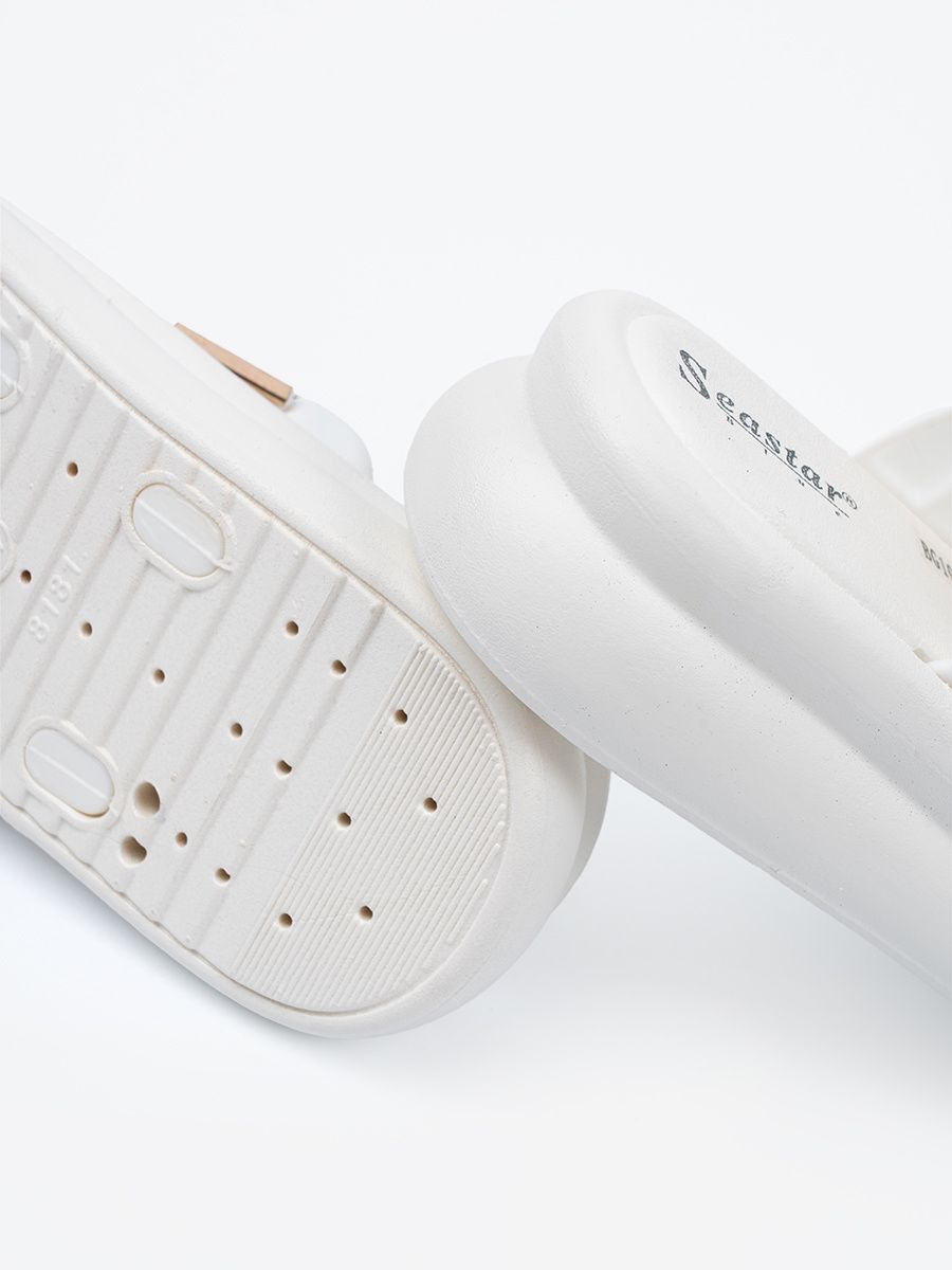 Weiße Pantoletten mit goldenen Schnallen auf der Plattform